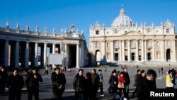 People walk in St. Peter's Square at the Vatican, February 19, 2013. 