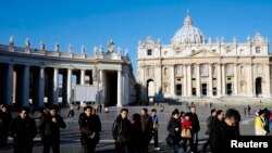 People walk in St. Peter's Square at the Vatican, February 19, 2013. 