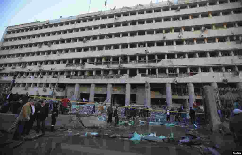 Police officers and people gather in front of the damaged Cairo Security Directorate after a bomb attack in downtown Cairo, Jan. 24, 2014. 