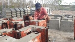 Seorang tukang sedang membuka cetakan panel beton p3 yang digunakan sebagai siku sambungan untuk kebutuhan hunian risha. (Foto: VOA/Yoanes Litha)