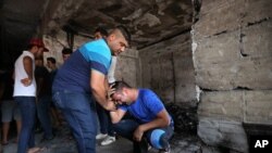 Iraqi men grieve at the scene of a deadly suicide car bomb at a commercial area in Karrada, Baghdad, July 4, 2016.