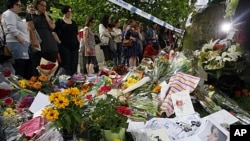 Fans gather around flowers and tributes near the home of British singer Amy Winehouse in London, July 25, 2011
