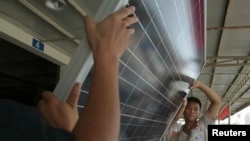 FILE - Employees examine newly-made solar panels before boxing for shipment at a factory of Yingli Solar in Baoding, Hebei province, August 2, 2012.