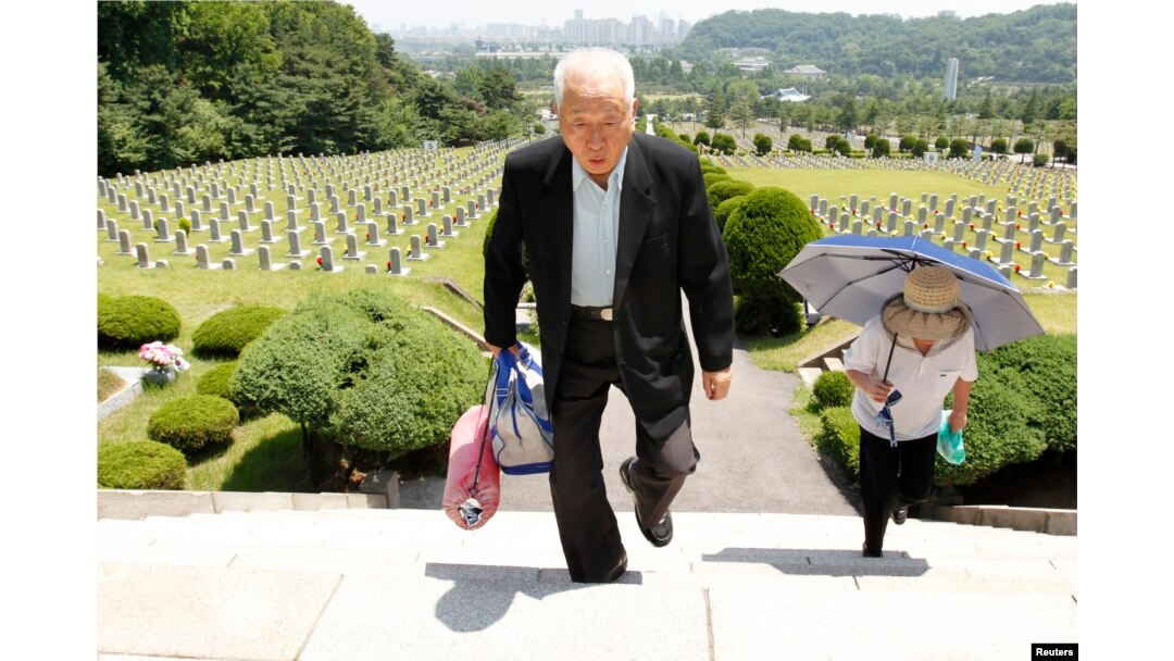 FILE - Ju Hong-jang, 81, and his wife Yoon Bok-hee, 73, visit a gravestone of his father, Ju Bong-gyeom, a police officer who died in 1952 during the Korean War, at the National Cemetery in Seoul, June 23, 2010. Ju's father took part in a bloody suppression operation to clear anti-government protesters and communists on Jeju island.