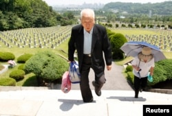 FILE - Ju Hong-jang, 81, and his wife Yoon Bok-hee, 73, visit a gravestone of his father, Ju Bong-gyeom, a police officer who died in 1952 during the Korean War, at the National Cemetery in Seoul, June 23, 2010. Ju's father took part in a bloody suppression operation to clear anti-government protesters and communists on Jeju island.