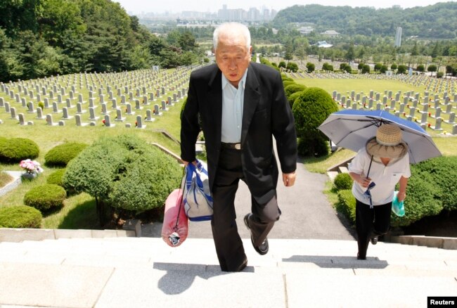 FILE - Ju Hong-jang, 81, and his wife Yoon Bok-hee, 73, visit a gravestone of his father, Ju Bong-gyeom, a police officer who died in 1952 during the Korean War, at the National Cemetery in Seoul, June 23, 2010. Ju's father took part in a bloody suppression operation to clear anti-government protesters and communists on Jeju island.