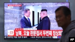 FILE - A TV screen shows South Korean President Moon Jae-in, left, meeting with North Korean leader Kim Jong Un at the border village of Panmunjom during a news program at the Seoul Railway Station in Seoul, South Korea, May 26, 2018. Moon and Kim are to meet again in September.