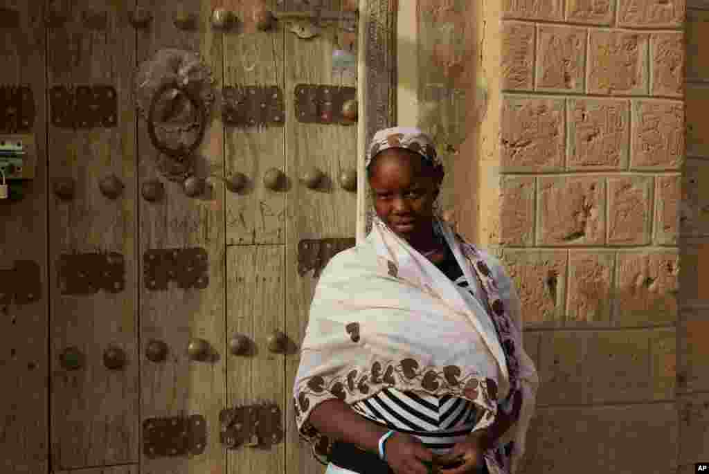 这张2012年5月1日拍摄的照片显示，一名女子在马里廷巴克图一个按照当地传统装饰的门前。
