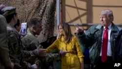 President Donald Trump and first lady Melania Trump greet members of the military as they arrive for a hangar rally at Al Asad Air Base, Iraq, Dec. 26, 2018. 