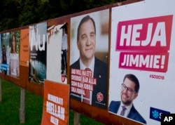 This photo shows an election poster or Jimmie Akesson, right, leader of the far-right Sweden Democrats, and Social Democratic Prime Minister Stefan Lofven, second from right. in Flen, Sweden, Aug. 30, 2018.