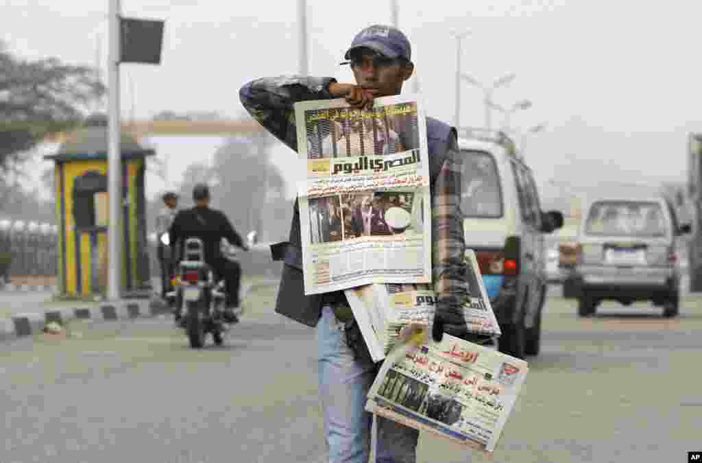 Seorang penjual koran Mesir di Kairo menjajakan surat kabar pagi dengan gambar pengadilan terhadap Presiden terguling Mesir Mohammed Morsi.
