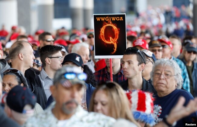 A man in the crowd holds a QAnon sign with the group's abbreviation of their rallying cry "Where we go one, we go all" as crowds gather to attend U.S. President Donald Trump's campaign rally at the Las Vegas Convention Center in Las Vegas, Nevada (Reuters/Patrick Fallon)