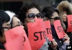 FILE - Defectors from North Korea cover their faces with placards as a safety precaution for their relatives still living in the North, during a protest in Seoul, South Korea, against human rights abuses in North Korea, Jan. 26, 2015.