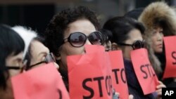 FILE - Defectors from North Korea cover their faces with placards as a safety precaution for their relatives still living in the North, during a protest in Seoul, South Korea, against human rights abuses in North Korea, Jan. 26, 2015.