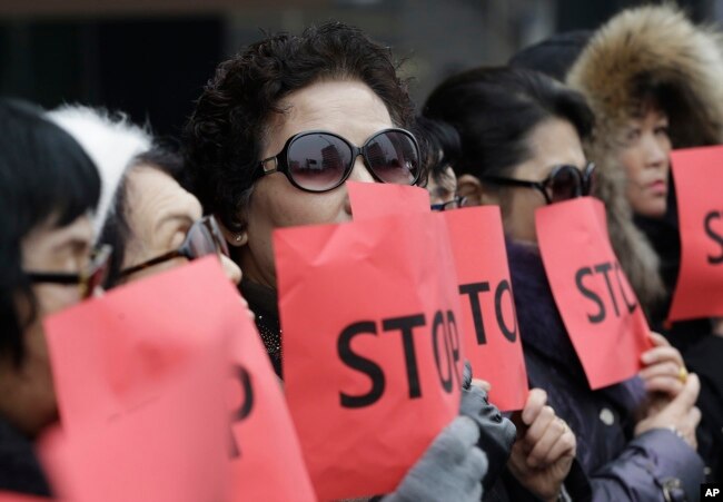 FILE - Defectors from North Korea cover their faces with placards as a safety precaution for their relatives still living in the North, during a protest in Seoul, South Korea, against human rights abuses in North Korea, Jan. 26, 2015.