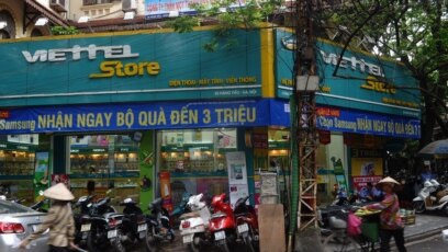 Một người bán hàng rong đi ngang một cửa hàng Viettel ở Hà Nội.