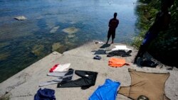 A Haitian migrant washes clothes in the Rio Grande after crossing a dam from Mexico to the United States, Sept. 17, 2021, in Del Rio, Texas.