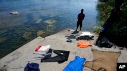 A Haitian migrant washes clothes in the Rio Grande after crossing a dam from Mexico to the United States, Sept. 17, 2021, in Del Rio, Texas.