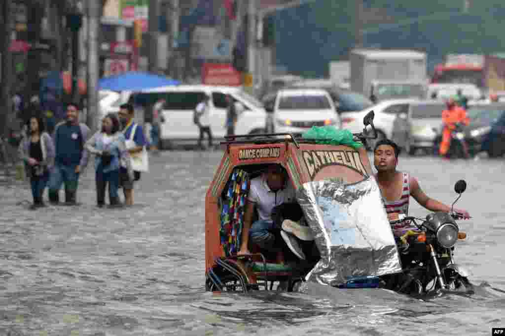 A commuter holding his shoes rides on a tricycle through a flooded street after a heavy downpour brought about by the southwest monsoon, in Manila, Philippines.