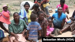 Women and their children in Mutare West wait as food is being cooked in December 2015 under FAO’s Livelihoods and Food Security Program in Zimbabwe.