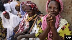 FILE - Women wait outside the workroom of the Multi-functional Platform for Poverty Alleviation in the village of Poa near Ougadougou in Burkina Faso.