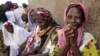 FILE - Women wait outside the workroom of the Multi-functional Platform for Poverty Alleviation in the village of Poa near Ougadougou in Burkina Faso.