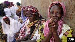 FILE - Women wait outside the workroom of the Multi-functional Platform for Poverty Alleviation in the village of Poa near Ougadougou in Burkina Faso.