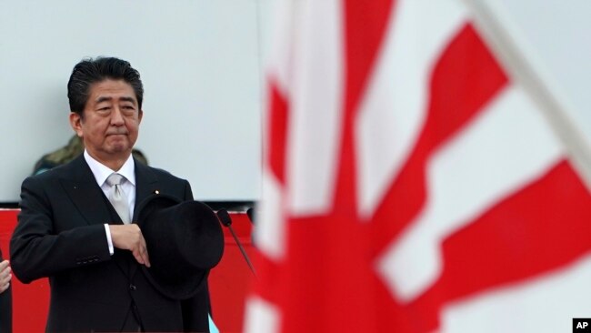 日本首相安倍晋三在日本某基地检阅日本自卫队成员。
