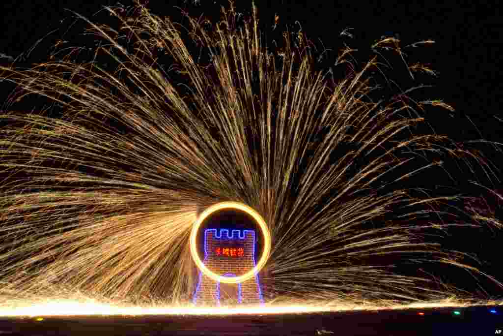 Performers turn a wheel at the Great Wall Iron Sparks show in Yanqing county on the outskirts of Beijing, China, Jan. 28, 2017.