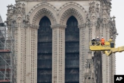 A crane lifts experts as they inspect the damaged Notre Dame cathedral after the fire in Paris, Apr. 16, 2019.