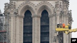 A crane lifts experts as they inspect the damaged Notre Dame cathedral after the fire in Paris, Apr. 16, 2019.