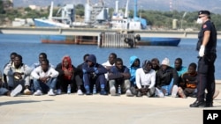 一批來自非洲的船民在意大利西西里島的一個港口等待接受檢查。