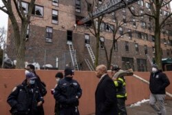 Walikota New York Eric Adams dan polisi New York tampak di luar sebuah apartemen yang dilanda kebakaran di Bronx, Minggu 9 Januari 2022.