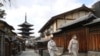 日本京都两名戴着口罩的妇女走过空荡荡的街头。（路透社2021年1月13日）