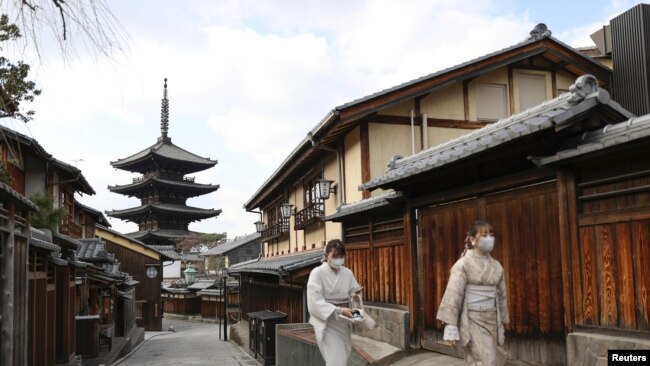 日本京都两名戴着口罩的妇女走过空荡荡的街头。（2021年月13日）