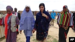 Pakistani activist Malala Yousafzai, center right, is welcomed by students and a staff from UNICEF during a visit to the camp of people displaced by Islamist extremists in Maiduguri, Nigeria, July. 18, 2017.