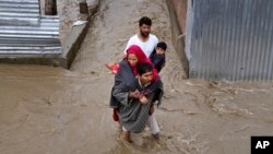 Kashmiri men assist a woman and a child to evacuate from a flooded area in Srinagar, Indian-controlled Kashmir, Monday, March 30, 2015.