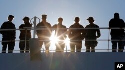 FILE - U.S. Navy personnel line the rails at Naval Station Norfolk, in Norfolk, Virginia, Dec. 18, 2018.