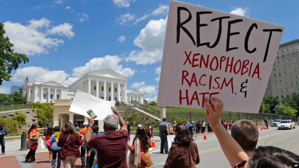 Protesters hold signs and march in front of the State Capitol across the street from the US 4th Circuit Court of Appeals in Richmond, Virginia, Monday, May 8, 2017.