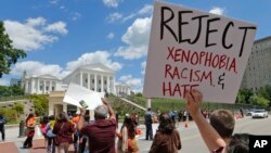 Protesters hold signs and march in front of the State Capitol across the street from the US 4th Circuit Court of Appeals in Richmond, Virginia, Monday, May 8, 2017.