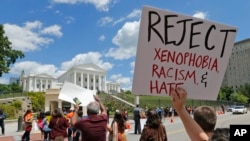 Protesters hold signs and march in front of the State Capitol across the street from the US 4th Circuit Court of Appeals in Richmond, Virginia, Monday, May 8, 2017.