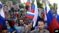 This photo from the Syrian official news agency SANA shows Syrians rallying in front of the Russian Embassy in Damascus to show their thanks to Russia for its intervention in Syria, Oct. 13, 2015. But few Syrians who leave their country are finding Russia welcoming. 