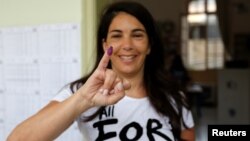 A woman shows her ink-stained finger after casting her vote during the parliamentary election in Beirut, Lebanon, May 6, 2018. 