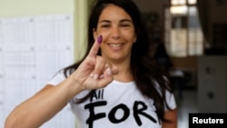 A woman shows her ink-stained finger after casting her vote during the parliamentary election in Beirut, Lebanon, May 6, 2018. 