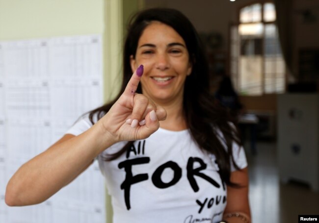 A woman shows her ink-stained finger after casting her vote during the parliamentary election in Beirut, Lebanon, May 6, 2018.