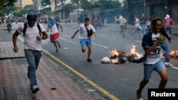 Opposition students run from Venezuelan police as they protest President Nicolas Maduro's government, Caracas, Feb. 12, 2015.