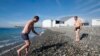 A man walks out of the sea after swimming during sunny spell at the Olympic Park in Sochi, Feb. 12, 2014.