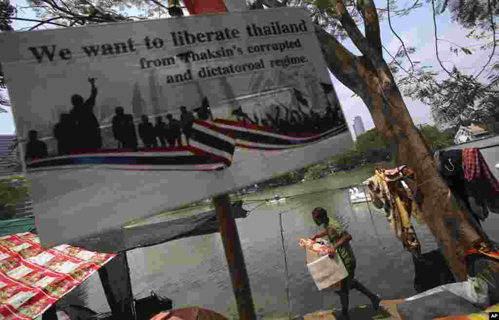 An anti-government protester carries a box containing his belongings at Lumpini Park in Bangkok, March 7, 2014. 