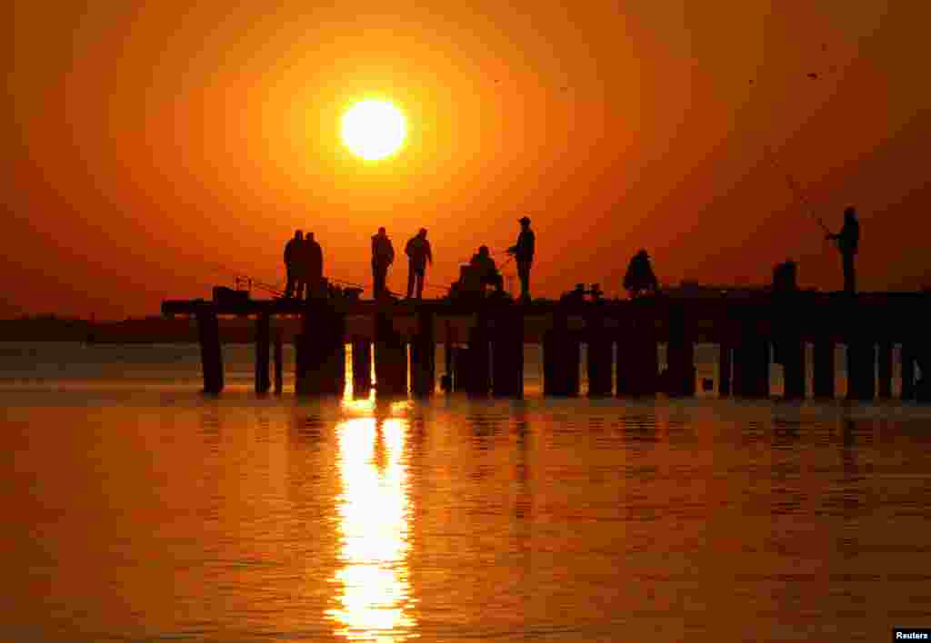 Fishermen gather on a mooring during sunset in Yevpatoriya, Crimea.