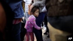 FILE - Nicole Hernandez, of the Mexican state of Guerrero, holds on to her mother as they wait with other families to request political asylum in the United States, across the border in Tijuana, Mexico. (AP Photo/Gregory Bull)